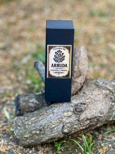 Embalagem preta de fluido de arruda sobre troncos de madeira