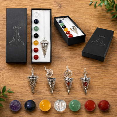 Conjunto de pêndulos com pedras coloridas em caixas pretas com a palavra Chakra numa mesa de madeira.