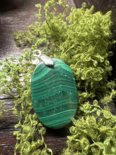 Pendente oval verde com suporte prateado sobre musgo verde