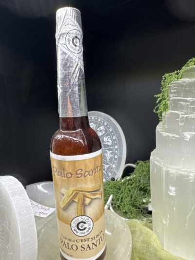 Frasco de vidro castanho rotulado Palo Santo entre cristais e musgo