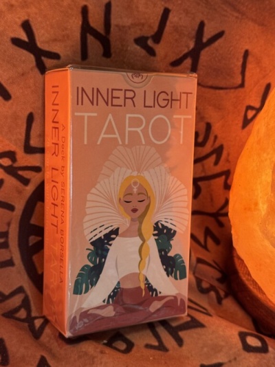 Caixa de tarot Inner Light com ilustração de mulher meditativa e fundo com símbolos