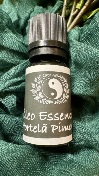 Frasco pequeno de óleo essencial Hortelã Pimenta com tampa preta sobre tecido verde