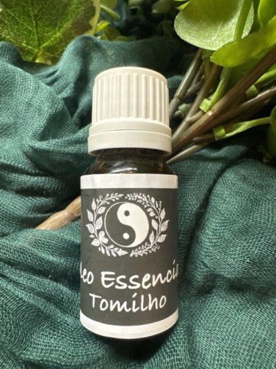 Frasco de óleo essencial de tomilho com rótulo preto e tampa branca sobre tecido verde