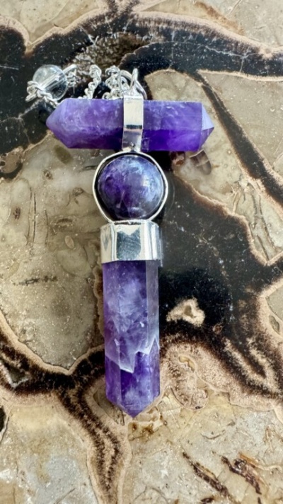 Colar com pendente em cristal violeta sobre pedra com padrões naturais