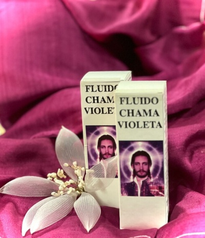 Embalagens do produto Fluido Chama Violeta sobre tecido violeta com flor branca decorativa