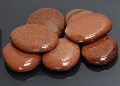 Pedras polidas castanho-dourado brilhantes sobre superfície preta