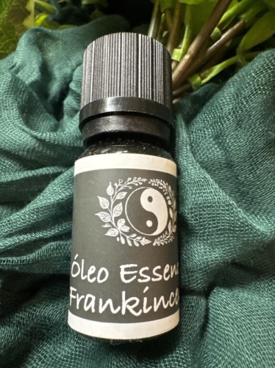 Frasco de óleo essencial Frankincense com tampa preta sobre tecido verde.