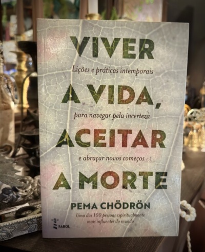 Livro Viver a Vida, Aceitar a Morte de Pema Chödrön numa mesa com objetos decorativos ao fundo