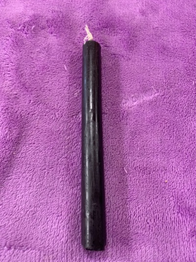 Vela preta sobre pano roxo