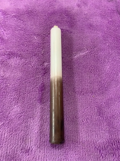 Vela bicolor castanha e branca sobre tecido roxo peludo