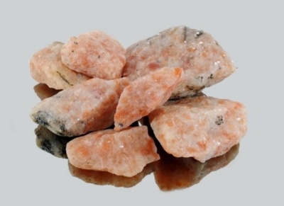 Pedras minerais rosas alaranjadas com textura rugosa em superfície reflexiva cinza.