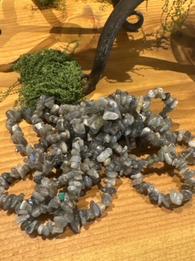 Pulseiras de pedras cinzentas sobre madeira com musgo e objeto de metal