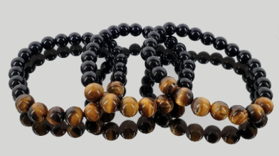 Pulseiras de contas pretas e castanhas com padrão em espiral sobre fundo cinzento