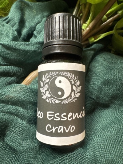 Frasco pequeno de óleo essencial com rótulo yin-yang e texto Cravo sobre tecido verde