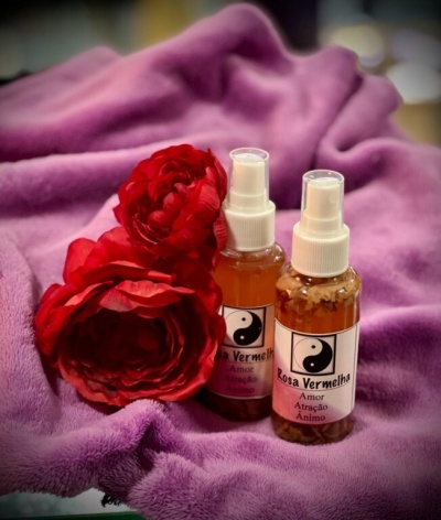 Dois frascos de spray com rótulos rosa vermelha e flores vermelhas sobre tecido roxo