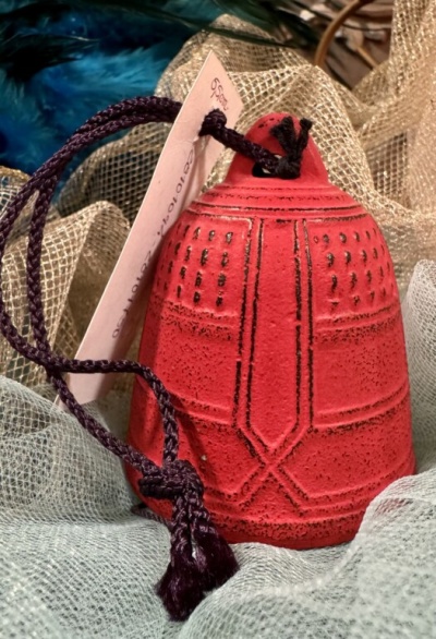 Sino vermelho decorativo com cordão roxo sobre tecidos translúcidos