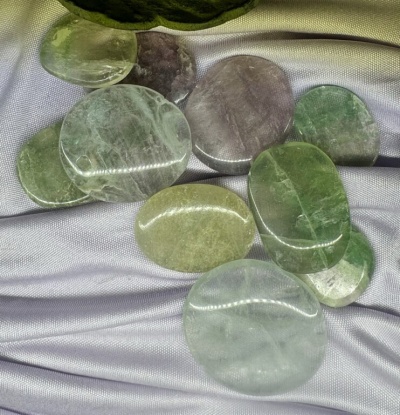 Pedras minerais polidas verdes e cinza sobre tecido cinzento prateado
