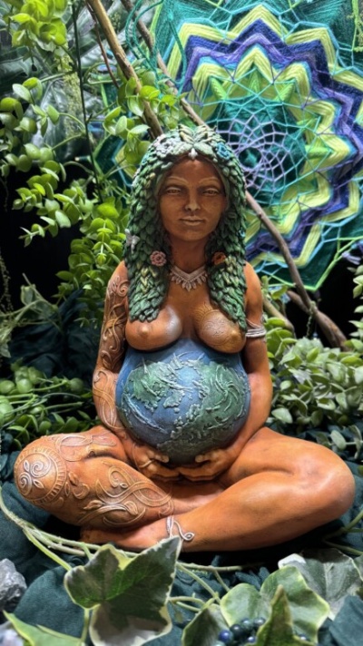 Estátua de mulher grávida com globo terrestre e cabelo verde trançado