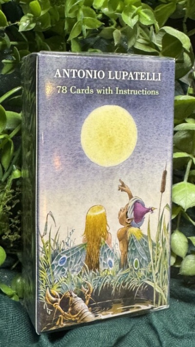 Caixa de baralho de tarot com ilustração de figuras junto a uma grande lua amarela e plantas verdes