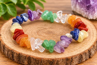 Pulseira colorida de pedras preciosas irregulares sobre tronco de árvore