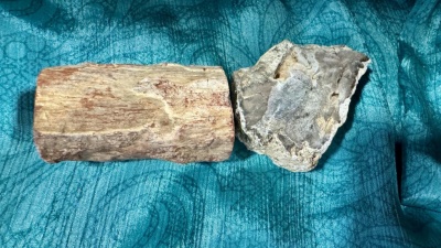 Dois objetos rústicos sobre tecido azul, um bloco de madeira e uma pedra cinzenta irregular