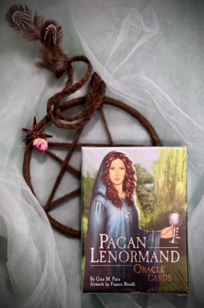Caixa de cartas oraculares Pagan Lenormand junto a pentagrama trançado com corda e penas
