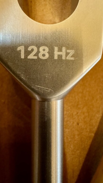 Diapasão metálico cinza com texto 128 Hz