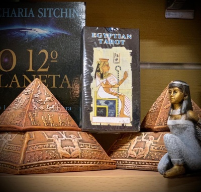Pirâmides decorativas, baralho Egyptian Tarot e estátua feminina egípcia sobre prateleira