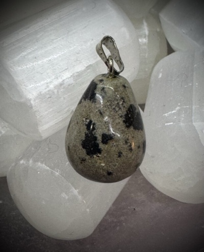 Pingente de pedra com padrão cinza e manchas negras sobre cristais brancos