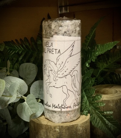 Vela cinza com etiqueta de cavalo alado e texto em português, sobre tronco de madeira com plantas ao fundo