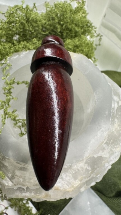 Objeto de madeira polida castanho escuro sobre suporte de cristal branco