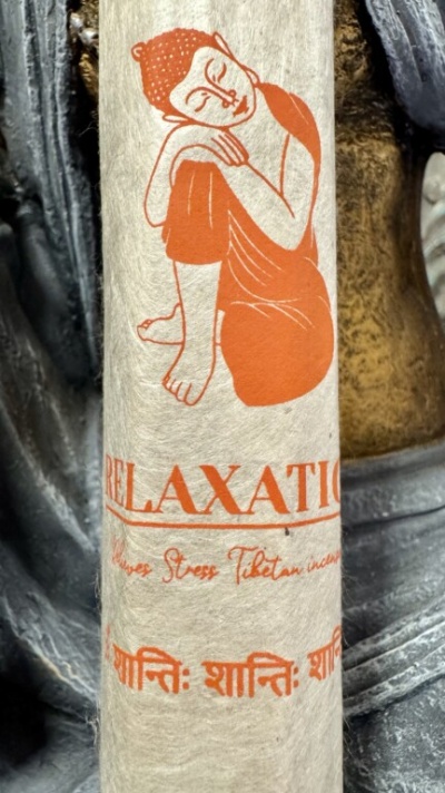 Pacote de incenso com figura meditativa e texto em laranja sobre papel bege texturizado