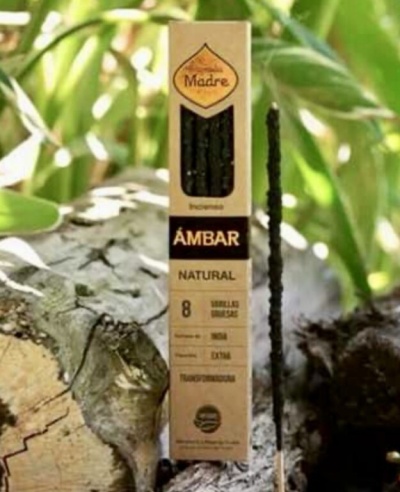 Embalagem de incenso Madre Âmbar Natural com uma vareta de incenso acesa ao lado