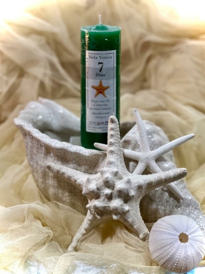 Vela votiva verde com etiqueta e conchas decorativas brancas