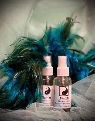 Duas garrafas de spray Alecrim com penas azuis e verdes ao fundo