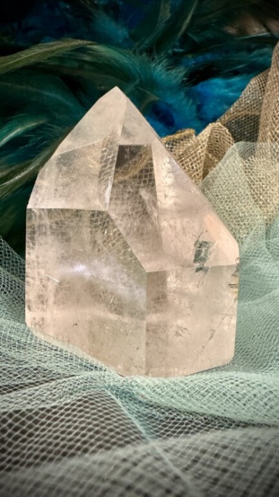 Cristal transparente sobre tecido de rede com penas coloridas ao fundo