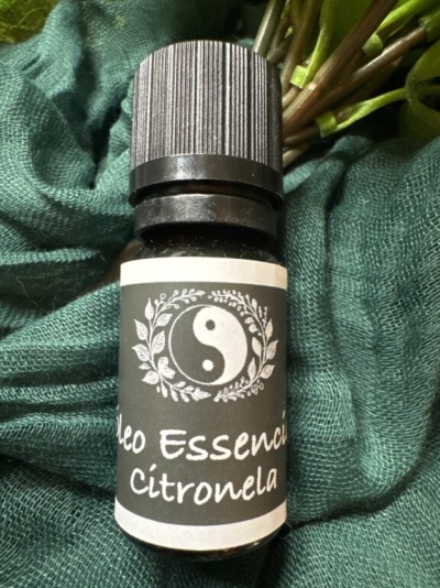 Frasco de óleo essencial de citronela com etiqueta preta e branca sobre tecido verde