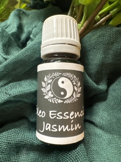 Frasco de vidro pequeno de óleo essencial de jasmim com rótulo preto e tampa branca sobre tecido verde.