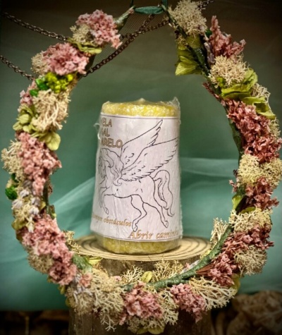 Vela amarela com rótulo de cavalo alado dentro de círculo floral decorativo