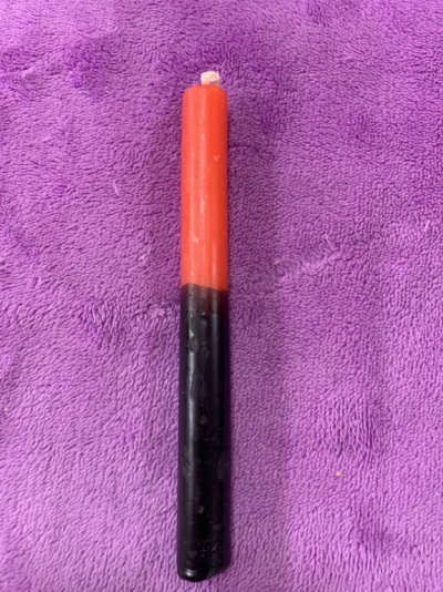 Vela vermelha e preta sobre tecido roxo