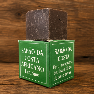 Barra de sabão castanha escura sobre caixa verde com texto em branco em fundo de madeira