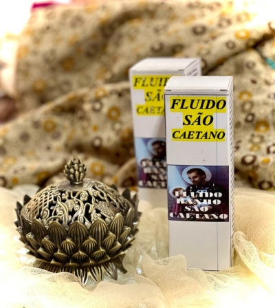Produto FLUIDO SÃO CAETANO e objeto decorativo dourado sobre tecido bege