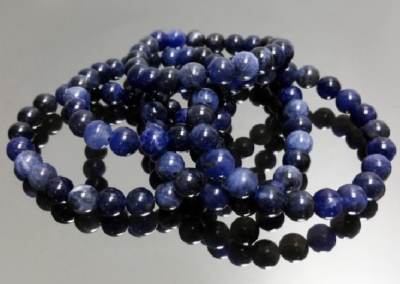 Pulseiras de contas de pedra azul sobre superfície espelhada