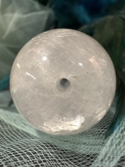 Esfera transparente de cristal com cavidade central sobre tecido azul e branco