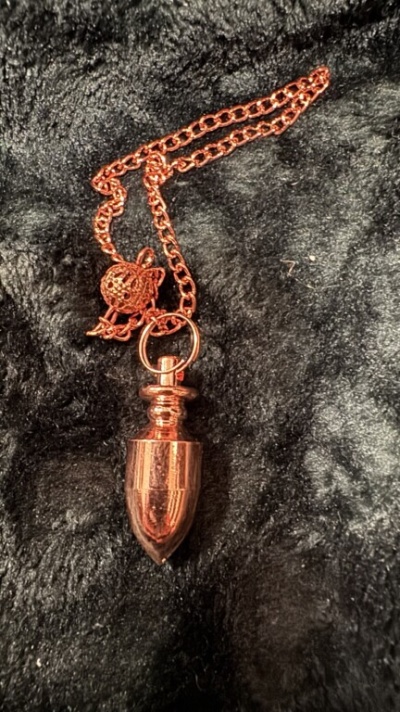 Colar com pendente cor cobre sobre tecido preto