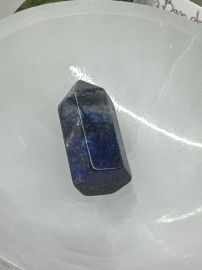 Cristal azul polido com acabamento facetado num prato branco