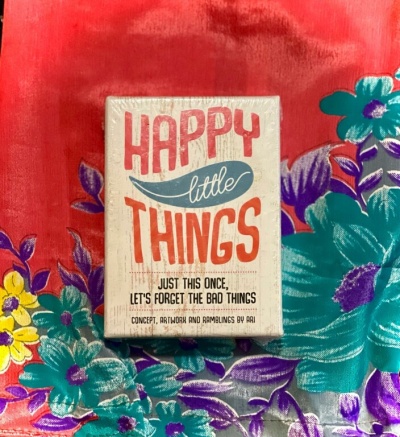 Caixa com texto Happy little Things sobre tecido floral vermelho