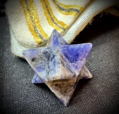 Escultura em forma de estrela de cristal azul, branco e cinzento sobre tecido cinzento e tecido cru com riscas amarelas