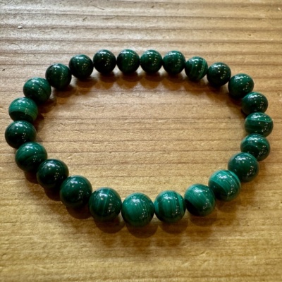 Pulseira verde de contas redondas sobre superfície de madeira clara