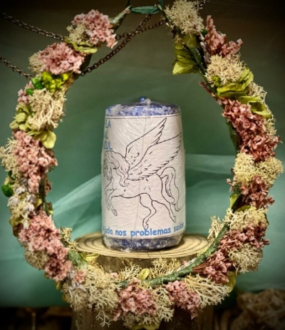 Frasco com esferas azuis e rótulo de pégaso rodeado por coroa de flores secas